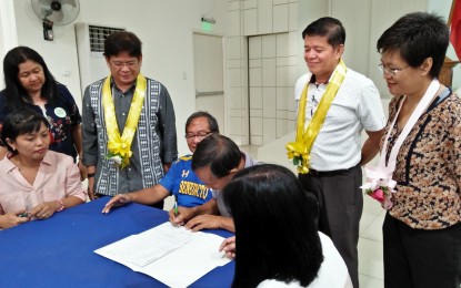 <p><strong>TURNOVER OF DOCUMENTS.</strong> Iloilo City Mayor Jose Espinosa III (left) and members of the Iloilo City Audit Transition Team  witness the signing of the turnover of documents from outgoing to incoming barangay officials of Jaro district on Tuesday (June 26, 2018). <em>(Photo by Perla Lena) </em></p>